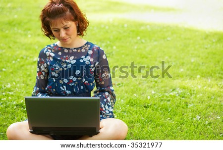 Young woman working on her laptop in nature.