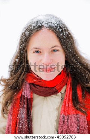 Smiling beautiful young woman with long brown hair in snow, outside on snowy day