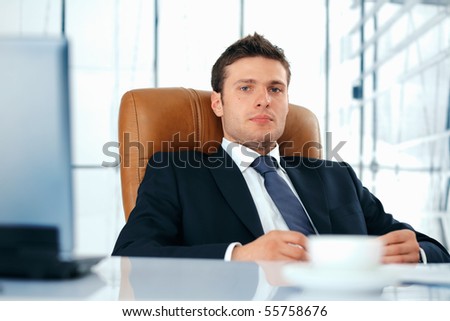 Young business executive sitting relaxed in chair looking at you.