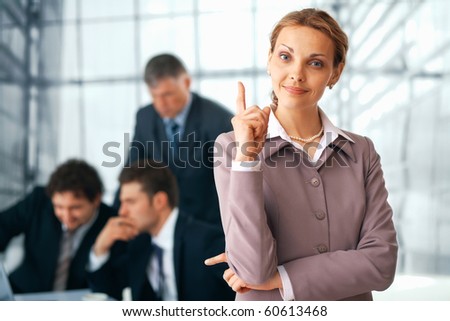 Portrait of a  happy businesswoman pointing upwards with her colleagues at the background.