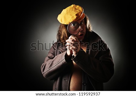 Surprised man with long hair and yellow cap looking through magnifying glass.