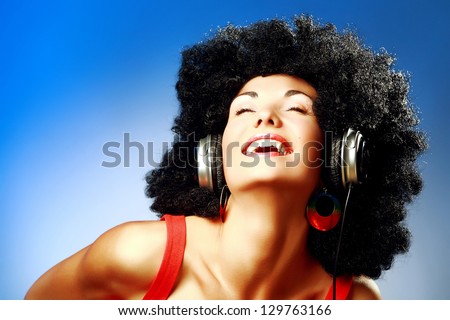 Happy woman with afro haircut enjoying music in headphones