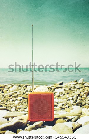 Orange radio set on the beach as old photography.