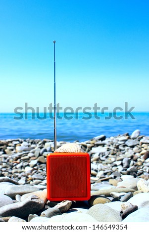 Orange radio set on the beach.