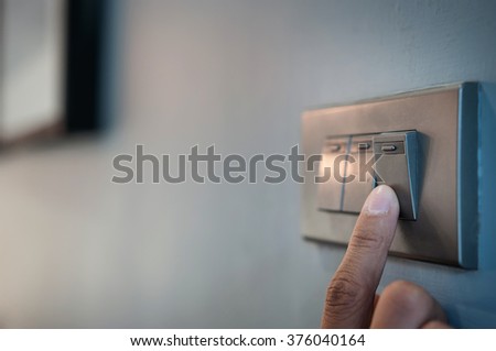 A finger is turning on a light switch.