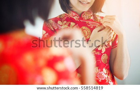 Chinese new year. Asian woman with cheongsam looking  to mirror. Girl is smiling. Get dress.