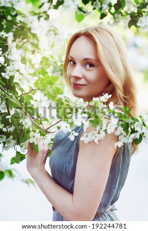 Fashion portrait of a young beautiful woman in flowers. Small amount of grain added for best final impression.