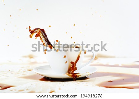 Cup of spilling coffee creating beautiful splash with stains on white. Coffee break, breakfast concept.