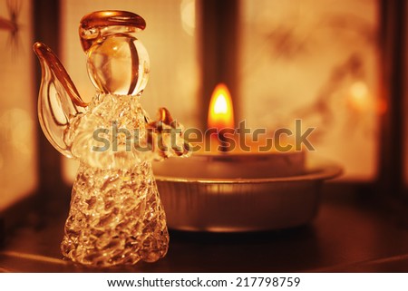 Christmas decoration with little glass angel and candle light. Image toned in vintage warm colors. Selective focus.