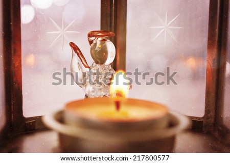 Christmas decoration with angel and candle light. Image toned in vintage warm colors. Selective focus. Dust, grain and scratches added for retro style.