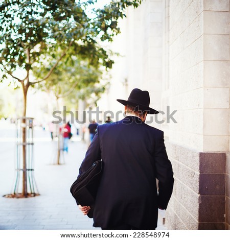 Jewish business man in the street with briefcase in his hand. Man turned his back.