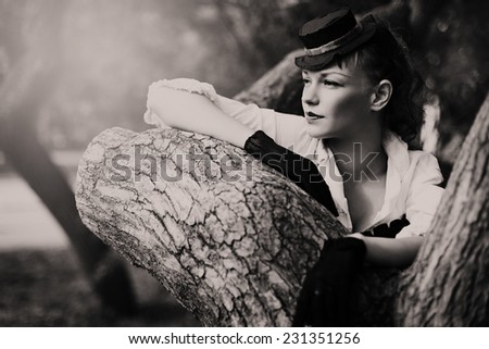 Black and white retro image of beautiful woman standing near tree. Summer, nature.