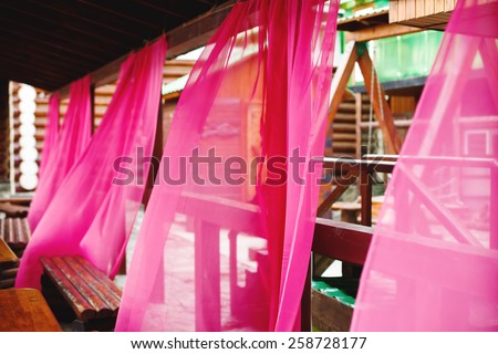 Bright pink curtains in street cafe waving in the wind. Abstract mood picture. Selective focus.