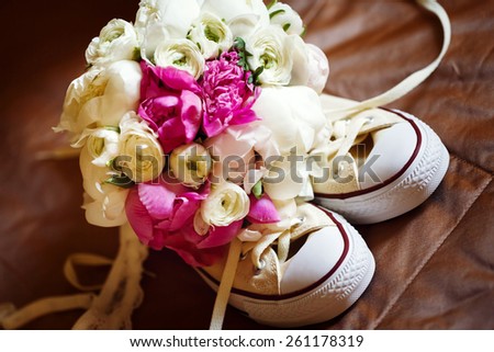 Wedding pink flowers with sneakers. Unusual wed accessories. Selective focus. Vintage color effect.