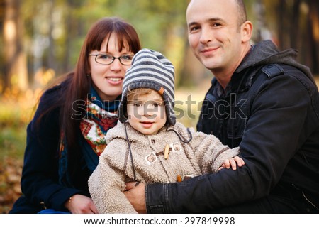 Happy Family Resting in the Park at the Day Time. 2 year Toddler Boy, Father and Mother Smiling and Looking To Camera. Selective Focus on a Kid.