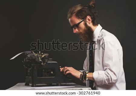 Handsome young hipster businessman thinking and writing with vintage typewriter. Old fashion style.