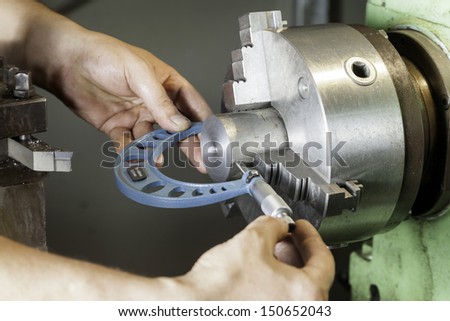 Operator measuring dimensions with a micrometer on a milling machine