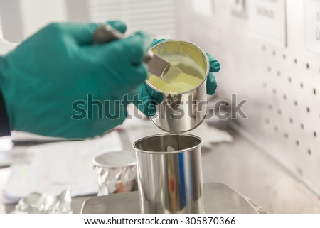 Technician weighing paint in a can by a balance
