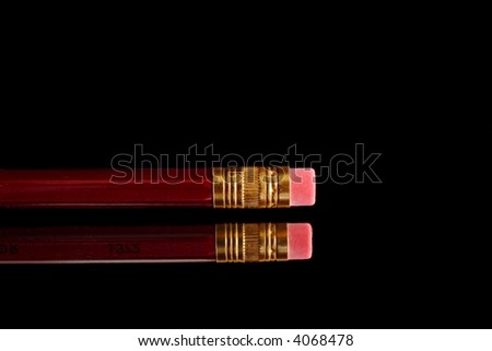 Red pencil with eraser on mirror over black background