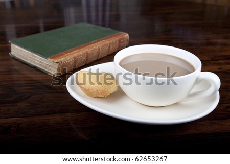 cup of coffee with an apple cake on saucer next to book on table