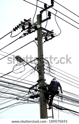 Worker climbing on Electrical concrete pole transmission line tower