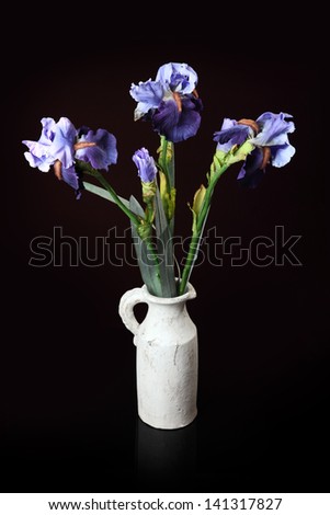 bouquet of artificial irises in a vase on a black background