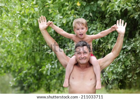 Ã?Â?Ã?Â  boy sitting on the shoulders of a man stretched hands on a bac