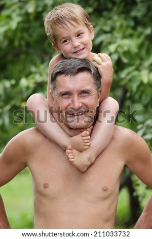 cute boy sitting on the shoulders of the man on a background of