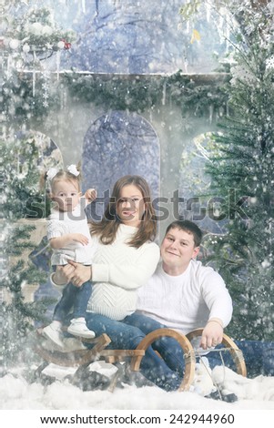 happy young family sitting in a sleigh on snow-covered terrace