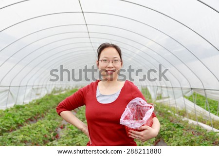girl in greenhouse with strawberry in hand