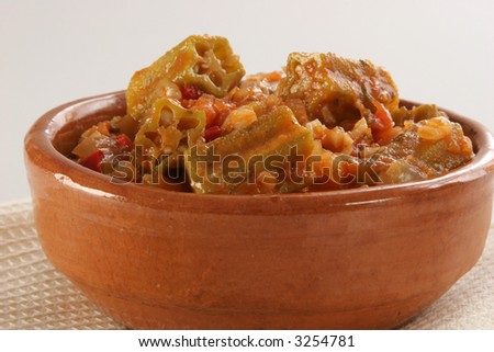 A recipe of okras (gumbos, Bamias) in mediterranean tomato\'s sauce with garlic, onion, chili, etc. with napkin