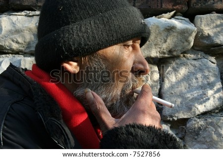 Portrait of old, poor man smoking cigarette