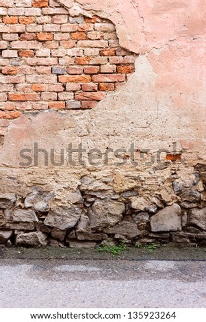 brick wall with chipped plaster, stone foundation and asphalt road