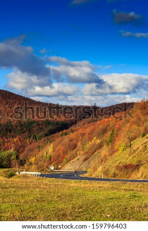 Autumn mountain landscape. S-curve road in the morning at the foot of the mountain. on the mountain forest with red and yellow leaves