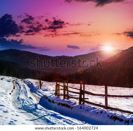 fence by the road to forest in the mountains on a fine winter sunset