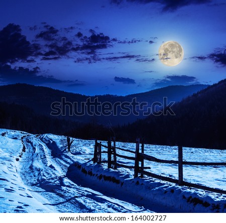 fence by the road to forest in the mountains on a fine winter night