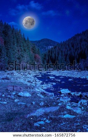 river flows by rocky shore near the autumn mountain forest at night