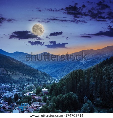 autumn landscape. village on the hillside. forest on the mountain light fall on clearing on mountains at night