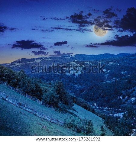 autumn landscape. village on the hillside. forest on the mountain light fall on clearing on mountains in moon light