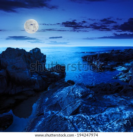 calm sea wave touch giant boulders on rocky shore at night in moon light