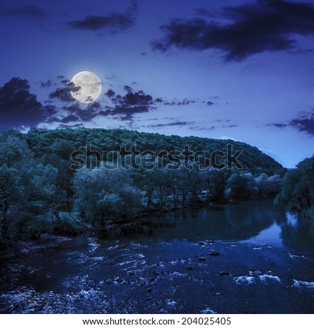 wild river flowing near the camping in  forest at the foot of mountain at night in moon light
