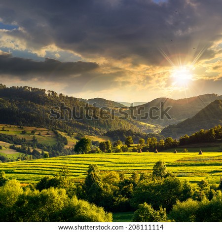 Summer land scape . Stack of hay on a green meadow in the mountains at sunset