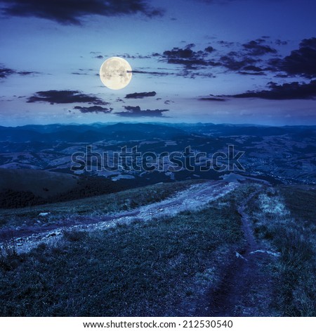 summer landscape. path goes from the mountain range down to village in valley at the mountain foot at night in full moon light