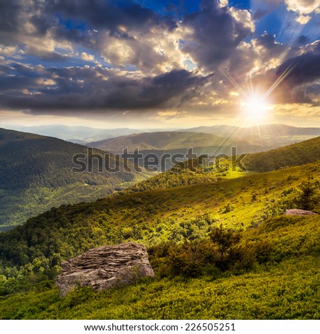 mountain landscape. valley with stones on the hillside. forest on the mountain under the beam of light at the top of the hill at sunset