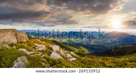 panoramic mountain landscape. valley with stones in grass on top of the hillside of mountain range in sunset light