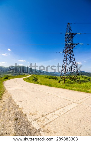High voltage electric power lines tower near the road in mountains