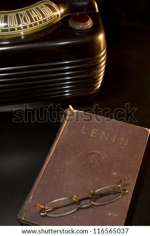 Lenin book on a table Composition of a vintage book of Vladimir Lenin with a pair of glasses and an old radio on a black table