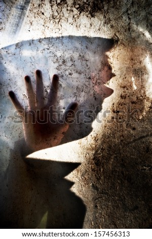 Man behind dirty window. A man behind dirty window in dark background having his palm against the glass