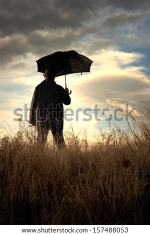 Man standing alone in the countryside watching at the cloudy horizon