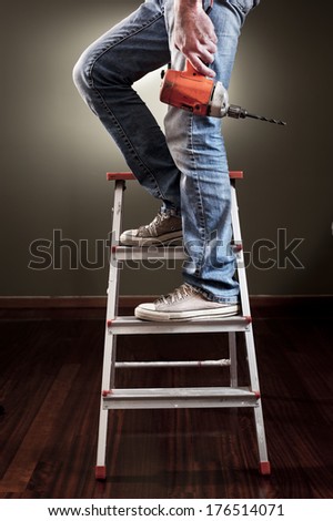 Man working on ladder with drill